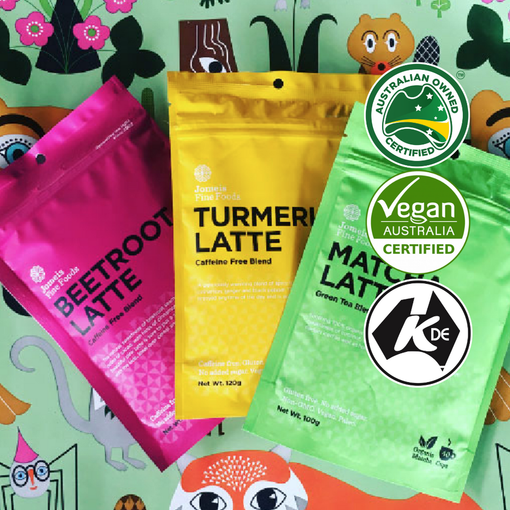 A trio of lattes in front of a playful background. The background features storybook characters, such as a fox, skirrel and spider. The lattes from left to right are beetroot, turmeric and matcha 