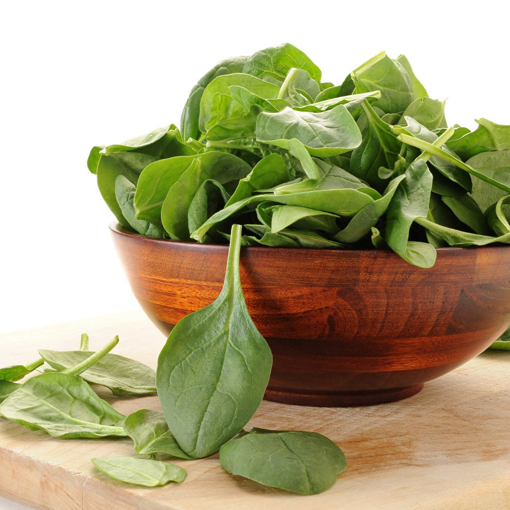 A wooden bowl filled with spinach leaves 