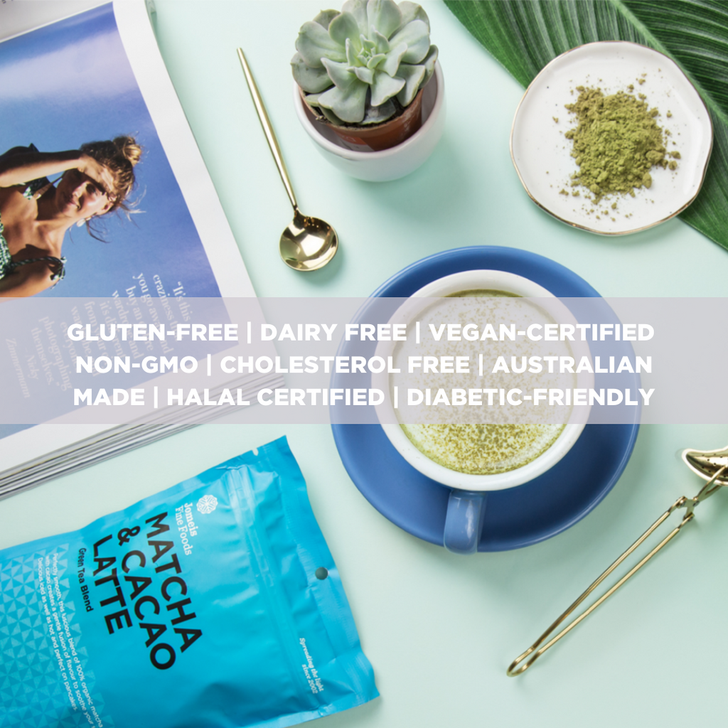 A blue-toned image with a matcha and cacao latte packet on the bottom left. Directly diagonal to the packet is a matcha and cacao latte which has matcha powder sprinkled on top of it. There is a magazine on the left of the screen and a succulent on top.