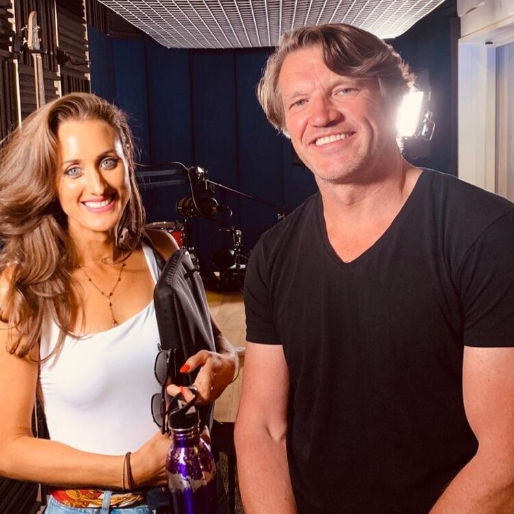 An image of David Burns and Jomeis Fine Foods Founder, Vicki Nguyen. They pair are standing in a studio together after recording the podcast episode. Vicki is wearing a white singlet and jeans and David is in black. They are both smiling at the camera
