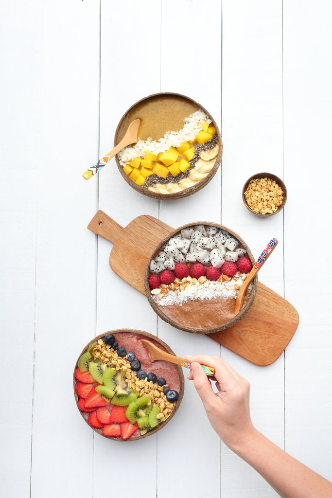 three superfood breakfast bowls from a birds-eye view. The top one is turmeric + ginger, the middle is cacao + coconut and the bottom is beetroot + cacao